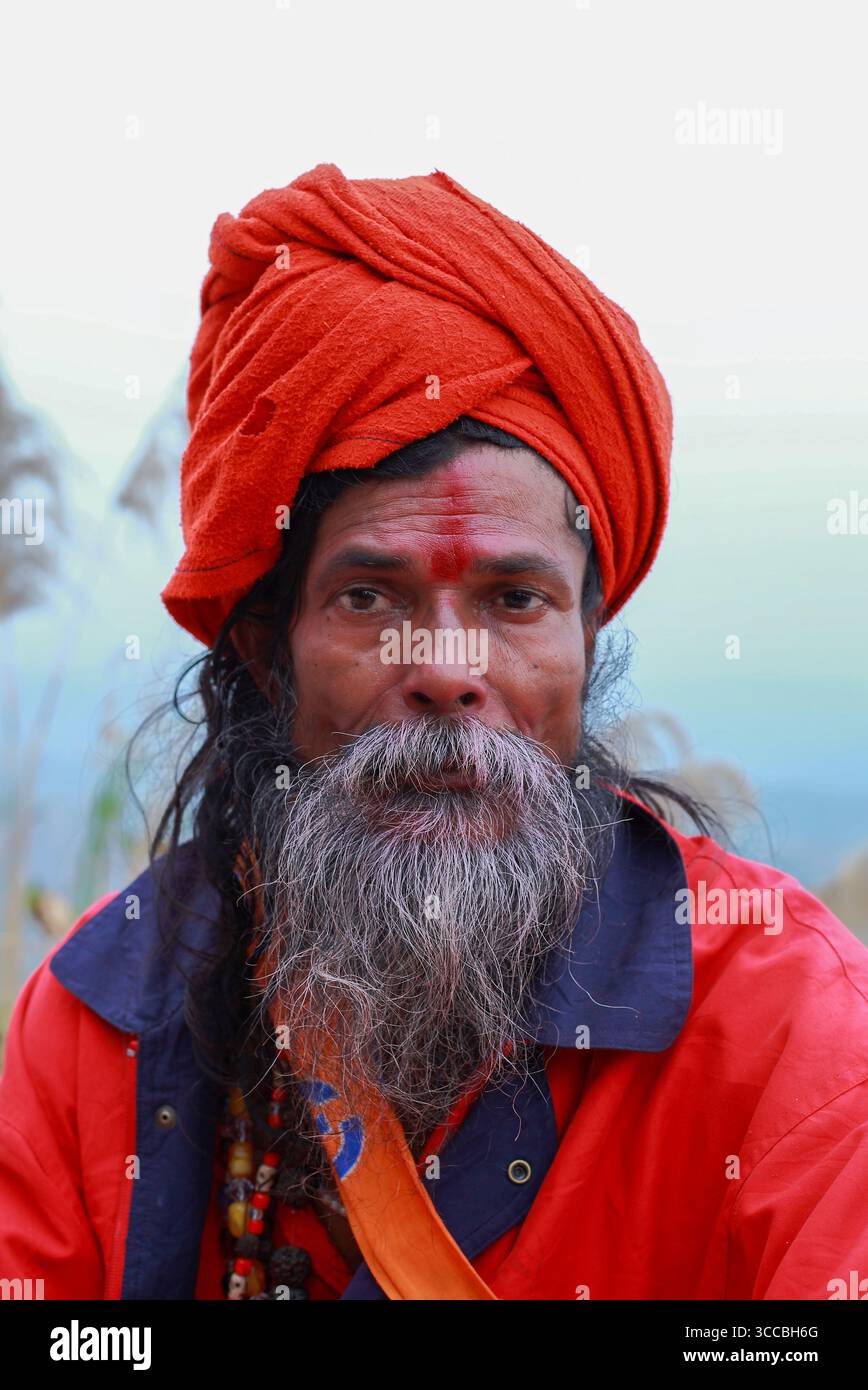 Chandanath hill, Bangladesh - 12 March 2021: View of a man with a striking orange turban and flowing grey beard, his weathered face bearing a red mark. Stock Photo