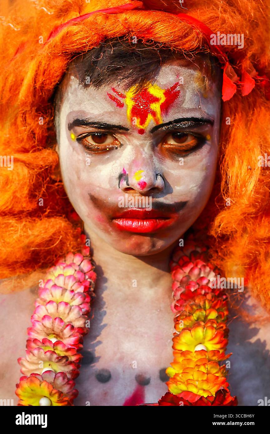 Chandanath hill, Bangladesh - 12 March 2021: View of a person adorned with vibrant orange hair and a garland, their face painted in stark white with s Stock Photo