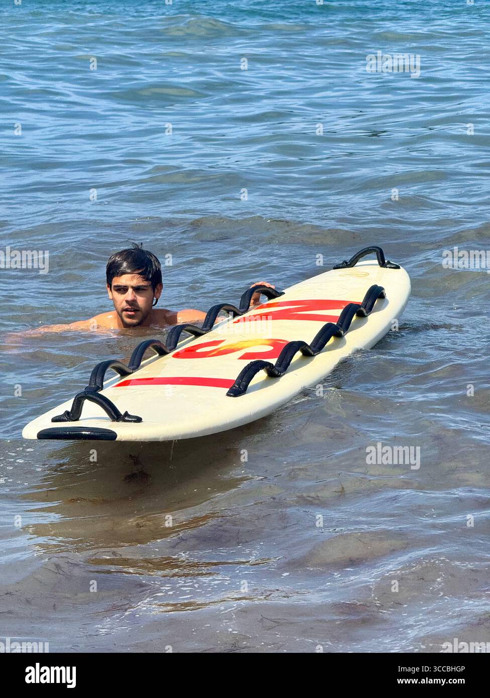 Lifeguard in the water holding a rescue board at a beach in the Azores, Portugal, ready for action. - Smartphone Captured Stock Image