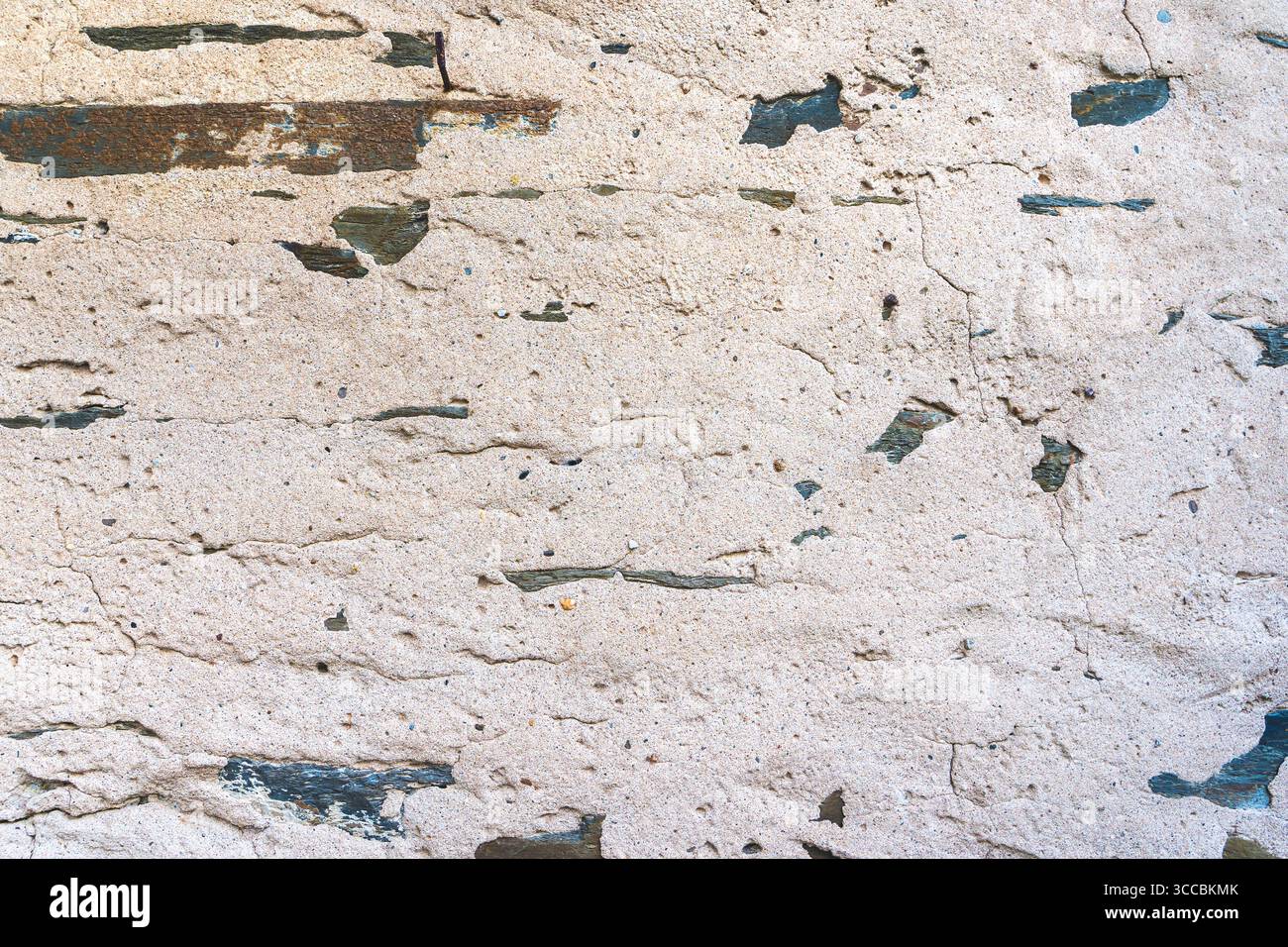 Old beige plaster wall texture with stone fragments and natural cracks. Stock Photo