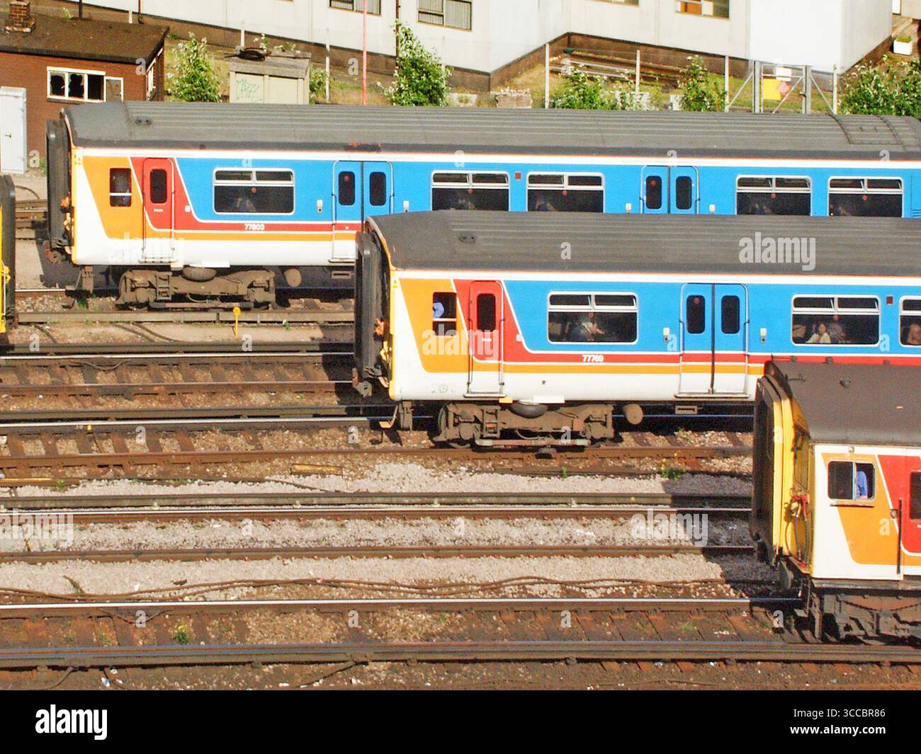 Aerial 2003 historical archive aerial view of drivers at work in cabs of three slow moving or stationary archival  red and blue colours of suburban passenger train services waiting just outside busy Waterloo terminal railway station for vacant platforms to become available in Lambeth Central London England UK Stock Photo