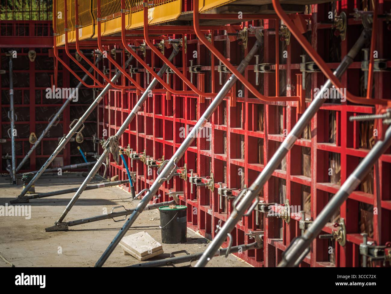 Workers are assembling concrete formwork at a construction site, using metal braces for support, ensuring stability during the building process. Stock Photo