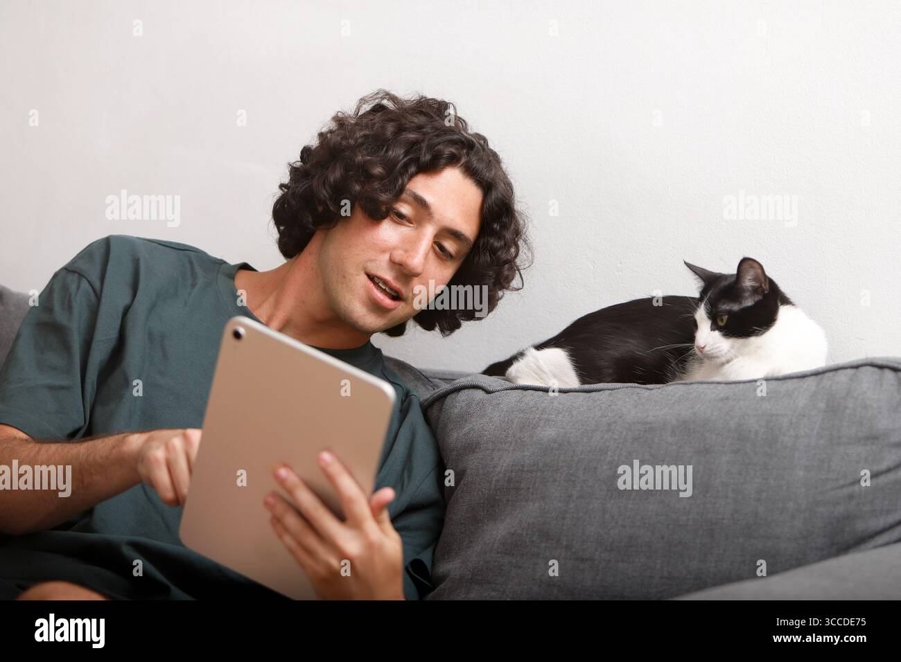 Young man using digital tablet with cat relaxing on sofa Stock Photo