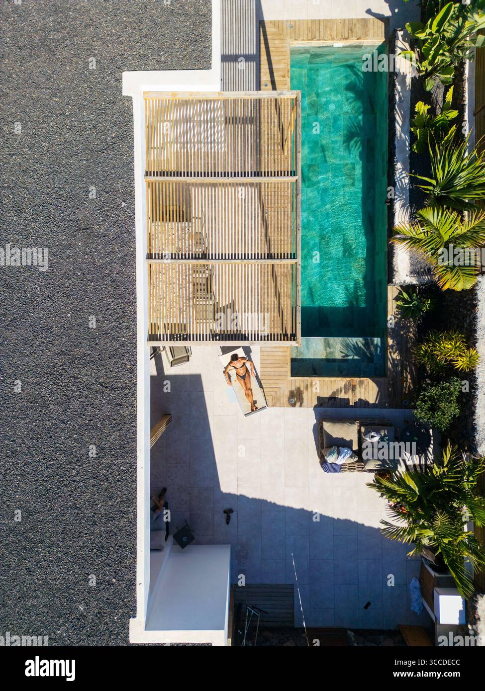 Aerial view of a woman sunbathing near a private swimming pool in a ...