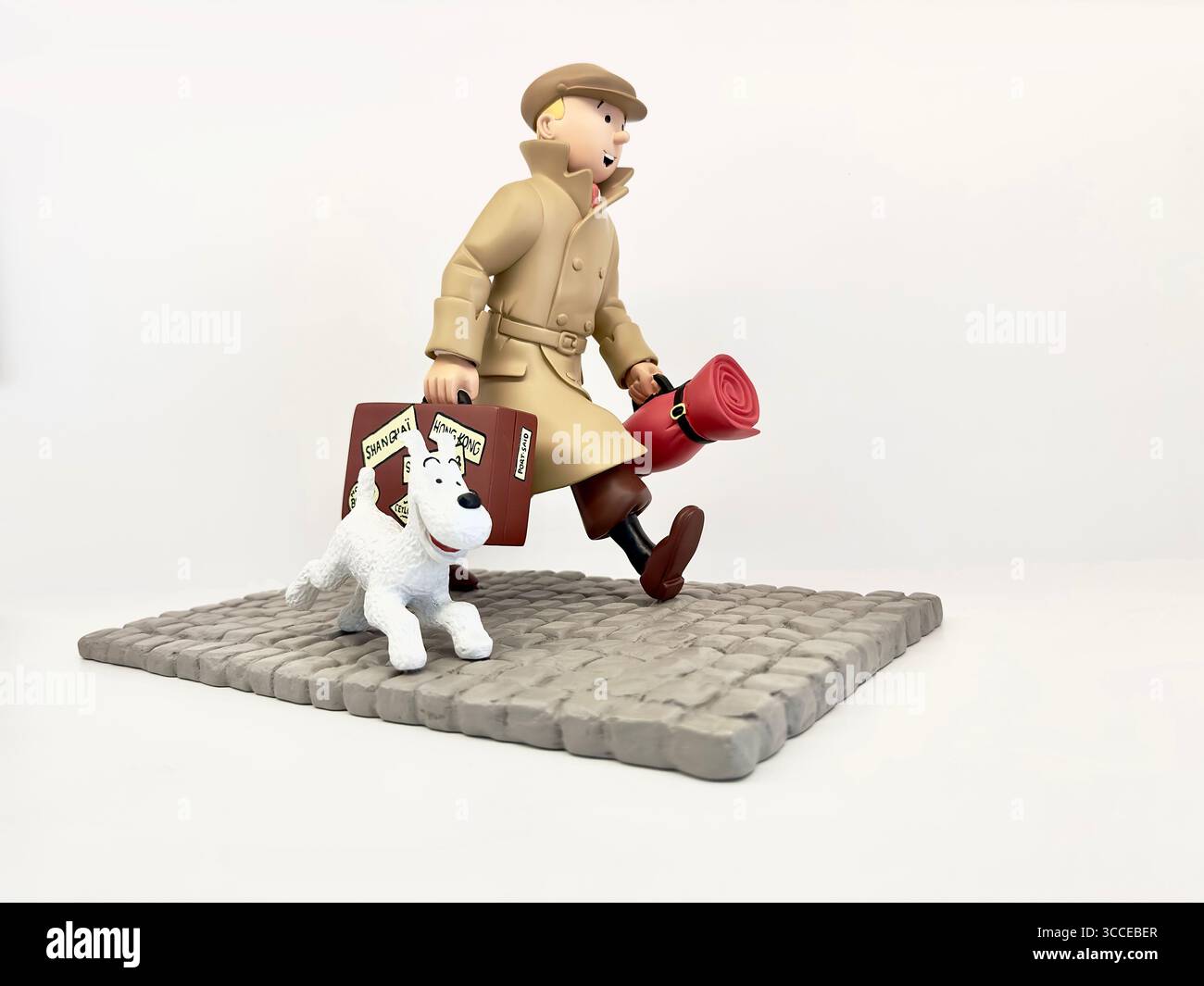 A Resin collectible figurine of Herge's cartoon detective Tintin in a trench coat and Snowy the dog on a cobblestone base - Smartphone Captured Stock Image
