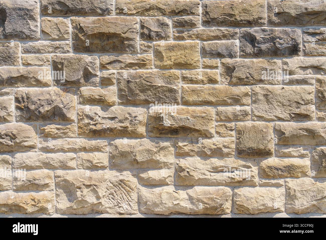 A close-up view of a textured beige stone wall with irregular rectangular blocks fitted together in a dry stack pattern. Stock Photo