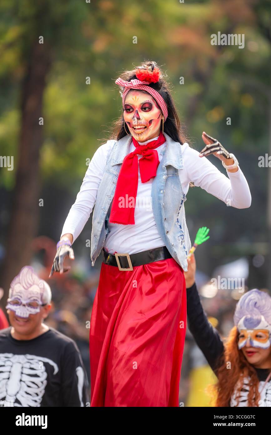 Mexico City, Mexico - November 2, 2024: Young Latina wearing an elaborate skull headdress and floral decorations during Mexico City's Day of the Dead Stock Photo