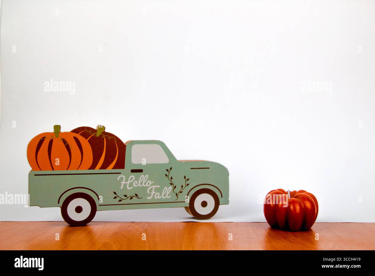 A decorative truck carrying pumpkins stands next to a pumpkin candle Stock Photo