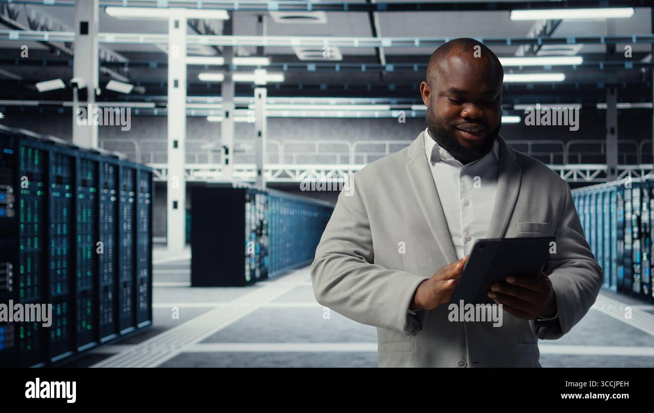 Server room worker troubleshooting server connectivity issues using software on tablet. Data center technician upgrading enterprise networks hardware using device, camera A Stock Photo