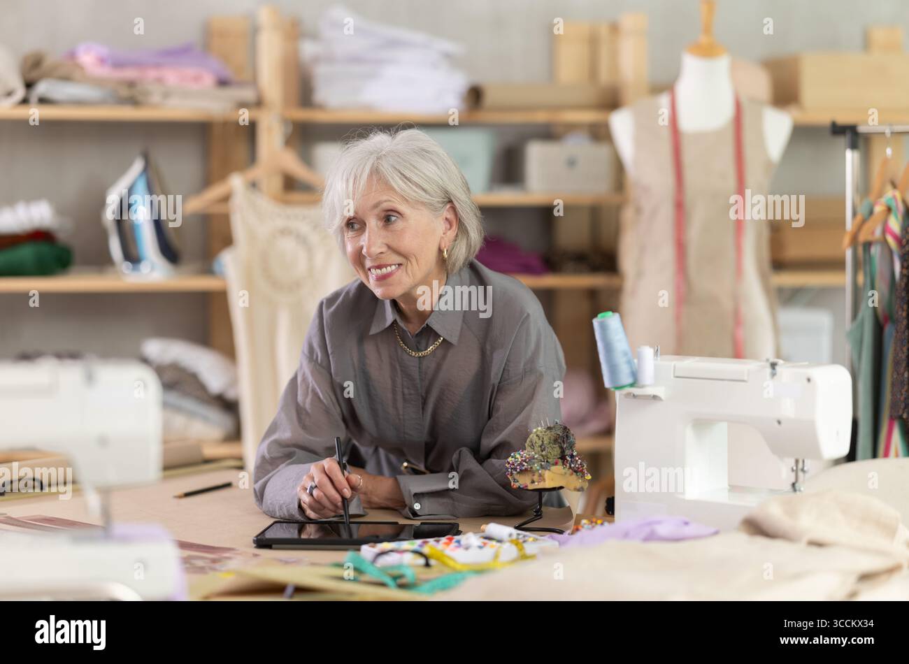 Woman dressmaker makes pattern using tablet Stock Photo