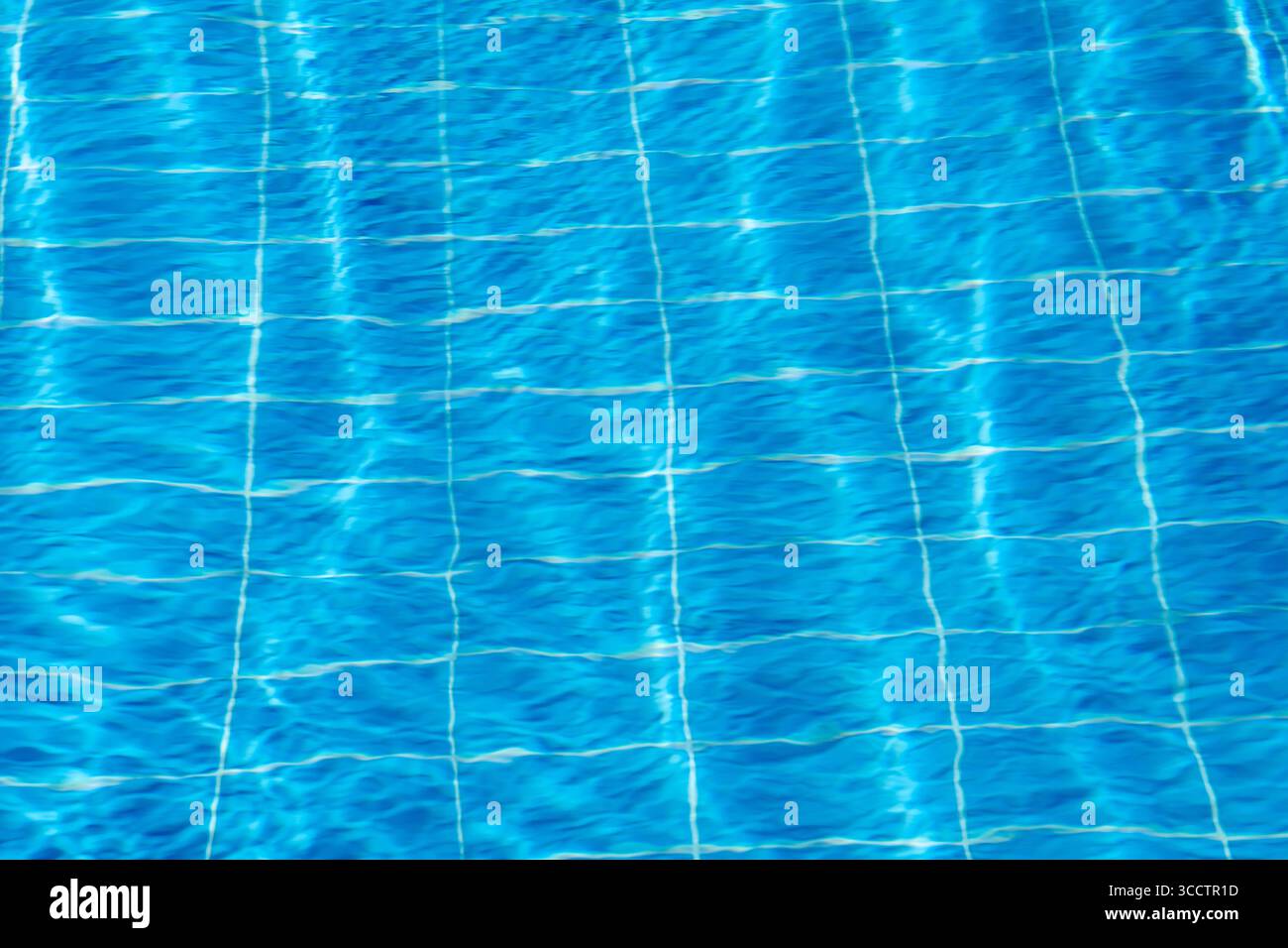 Sunlight glistens on the surface of a swimming pool, creating a vibrant ...