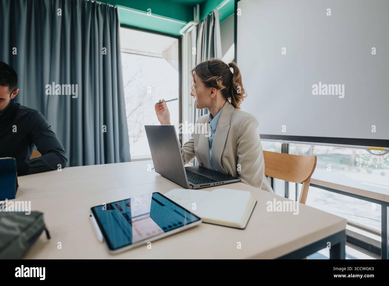 Colleagues collaborating in modern office space using laptops and digital devices Stock Photo