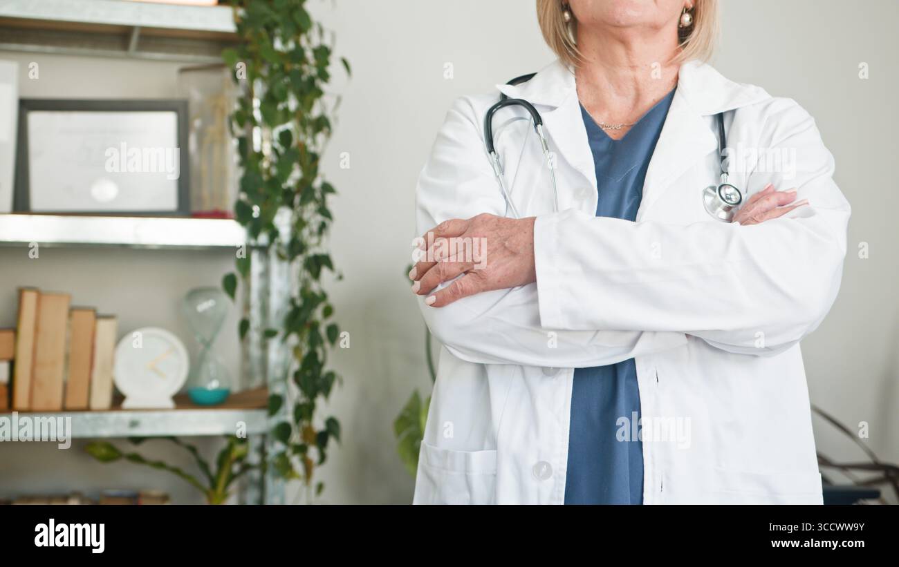 Confident Female Doctor Standing in Office Setting with Folded Arms Stock Photo