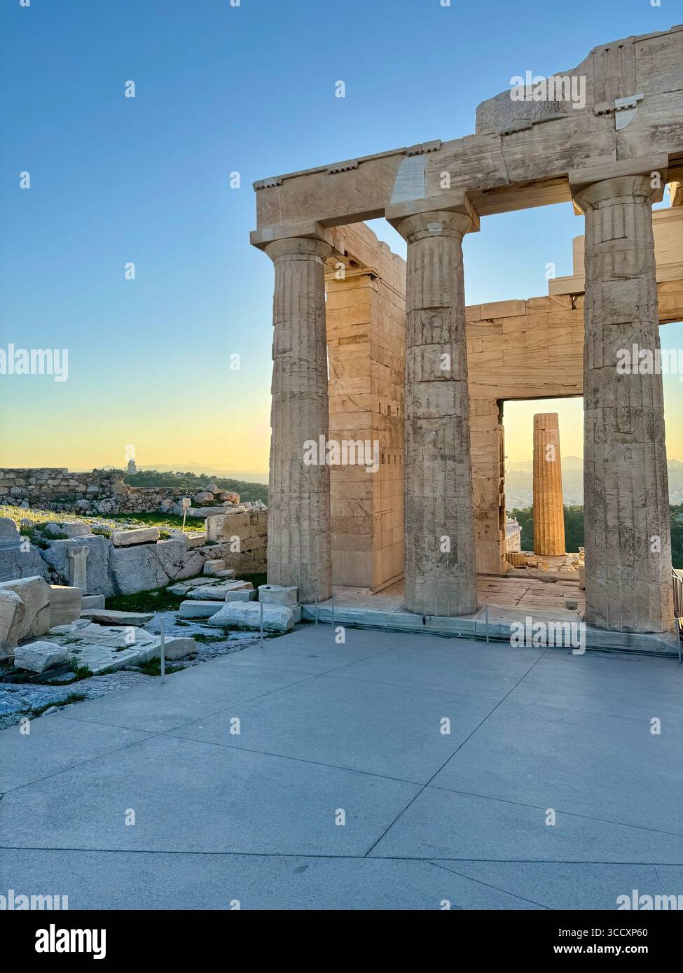Golden hour sunset at the entrance of the Acropolis complex (Acrópole Propileia) in Athens, Greece, with tourists walking down the stairs. - Smartphone Captured Stock Image