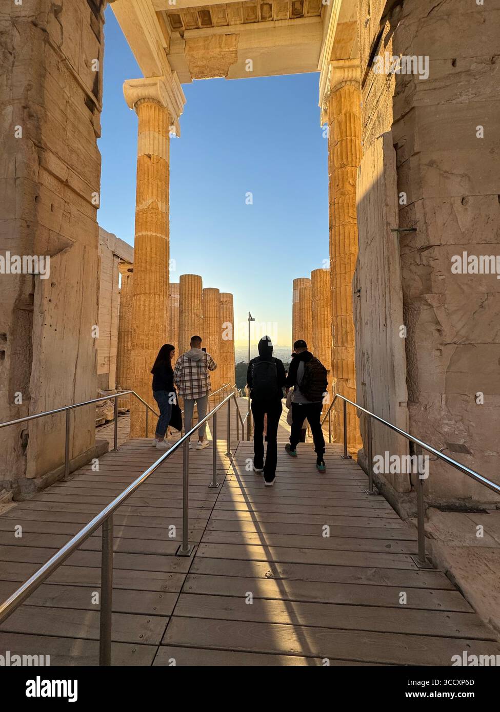 Golden hour sunset at the entrance of the Acropolis complex (Acrópole Propileia) in Athens, Greece, with tourists walking down the stairs. - Smartphone Captured Stock Image