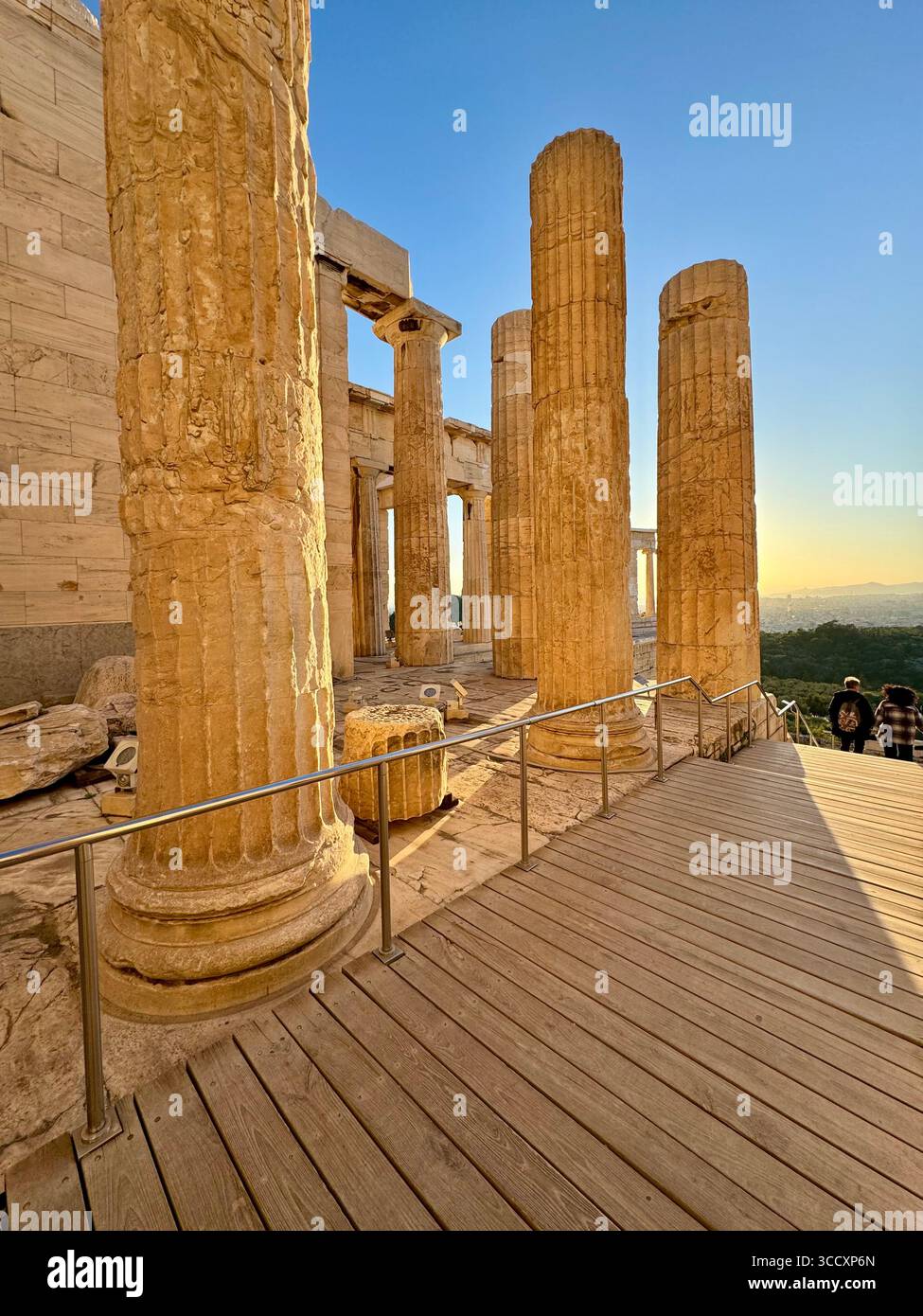 Golden hour sunset at the entrance of the Acropolis complex (Acrópole Propileia) in Athens, Greece, with tourists walking down the stairs. - Smartphone Captured Stock Image