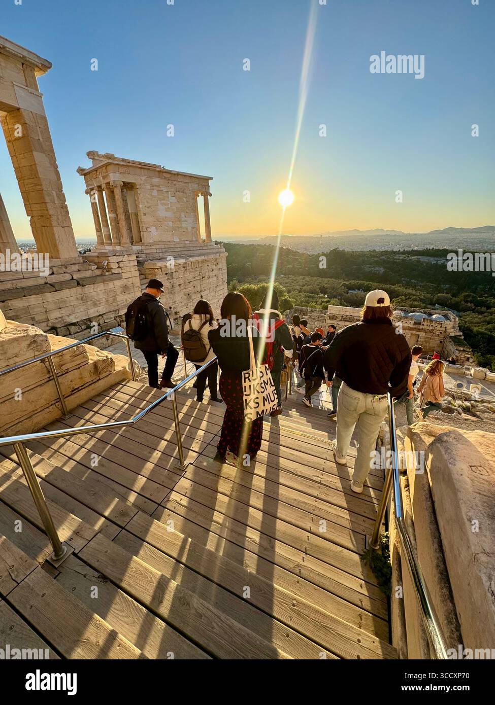 Golden hour sunset at the entrance of the Acropolis complex (Acrópole Propileia) in Athens, Greece, with tourists walking down the stairs. - Smartphone Captured Stock Image