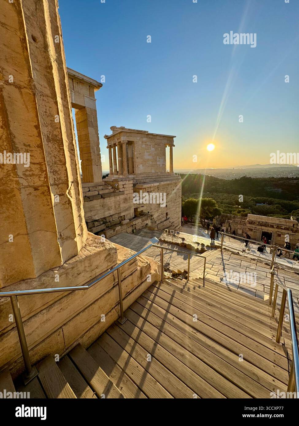Golden hour sunset at the entrance of the Acropolis complex (Acrópole Propileia) in Athens, Greece, with tourists walking down the stairs. - Smartphone Captured Stock Image