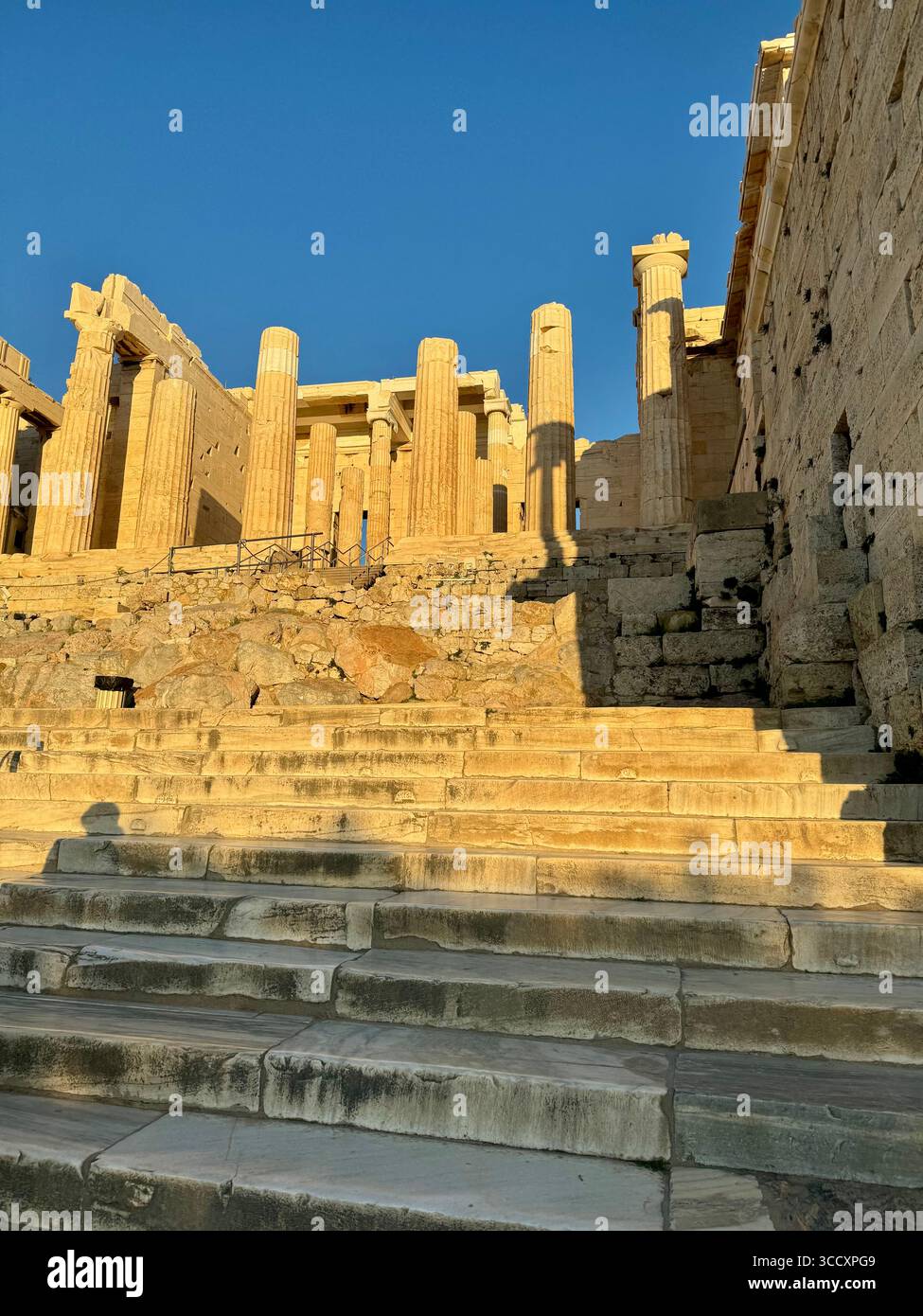 Golden hour sunset at the entrance of the Acropolis complex (Acrópole Propileia) in Athens, Greece, with tourists walking down the stairs. - Smartphone Captured Stock Image