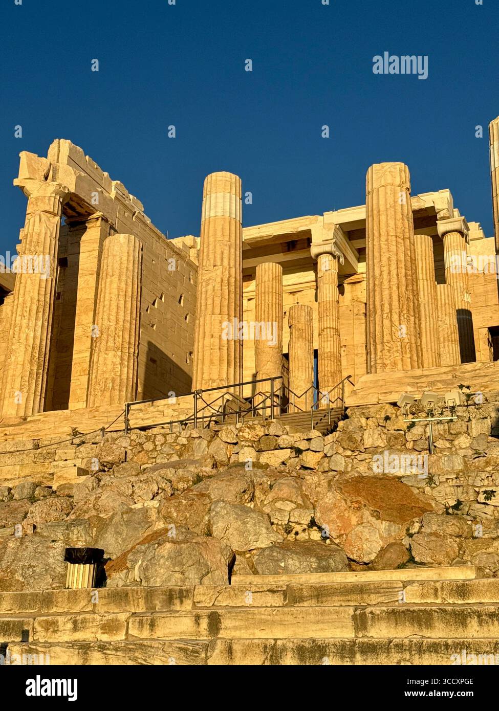 Golden hour sunset at the entrance of the Acropolis complex (Acrópole Propileia) in Athens, Greece, with tourists walking down the stairs. - Smartphone Captured Stock Image
