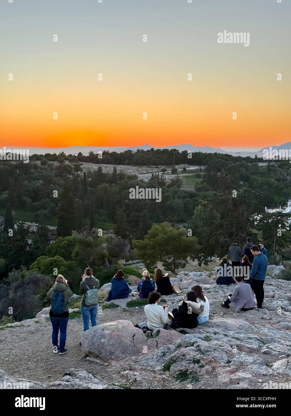 People enjoying the sunset at Areopagus Hill with a panoramic view of Athens in the background. - Smartphone Captured Stock Image
