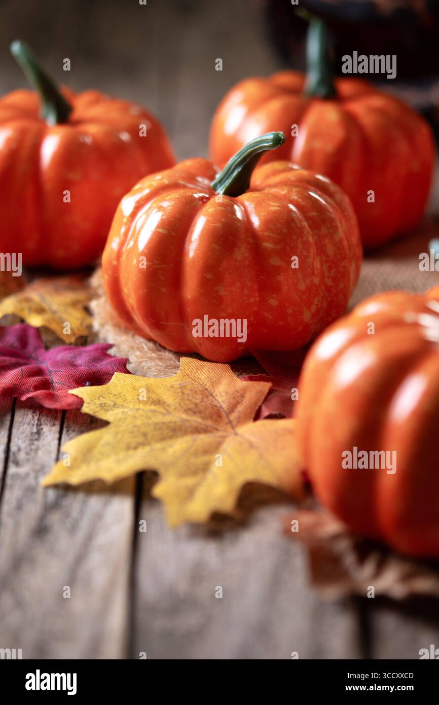 Small orange pumpkins on a rustic wooden table with scattered autumn ...