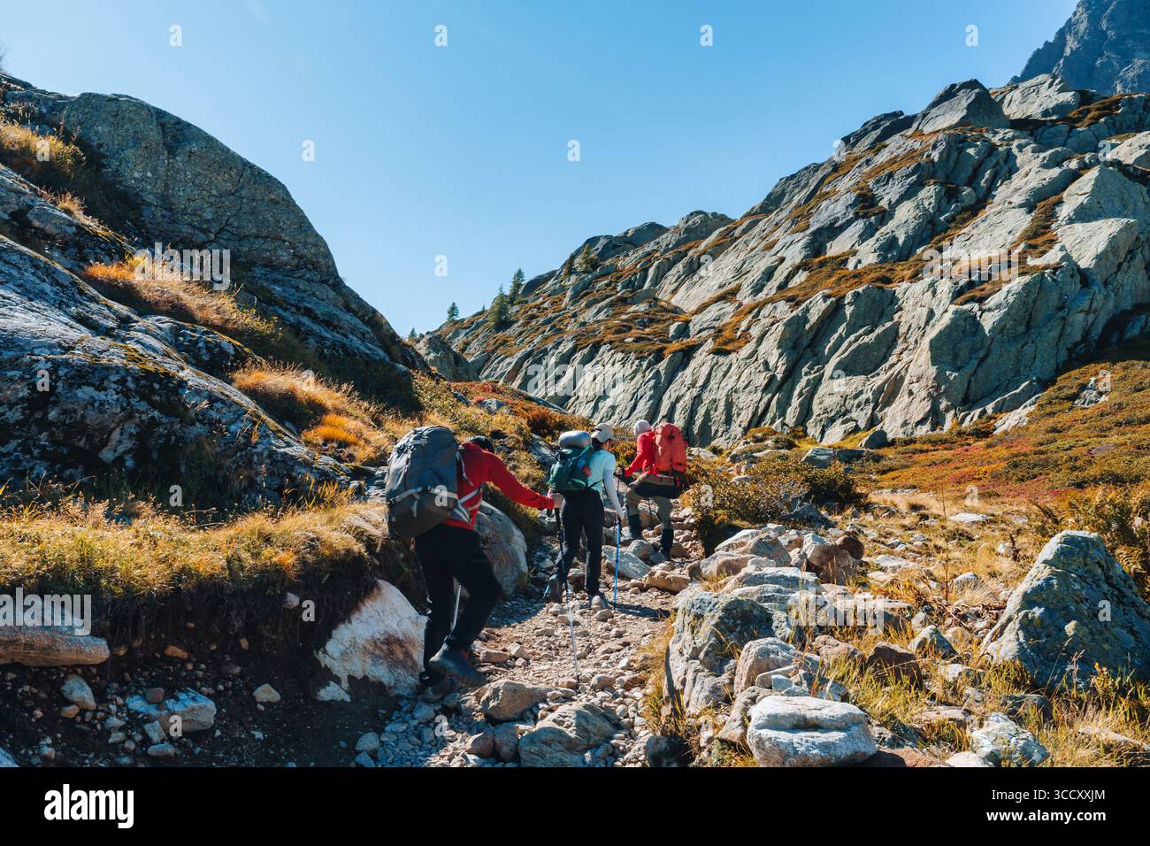 Group of hikers climbing challenging trail toward mountain peak among the French Alps Stock Photo