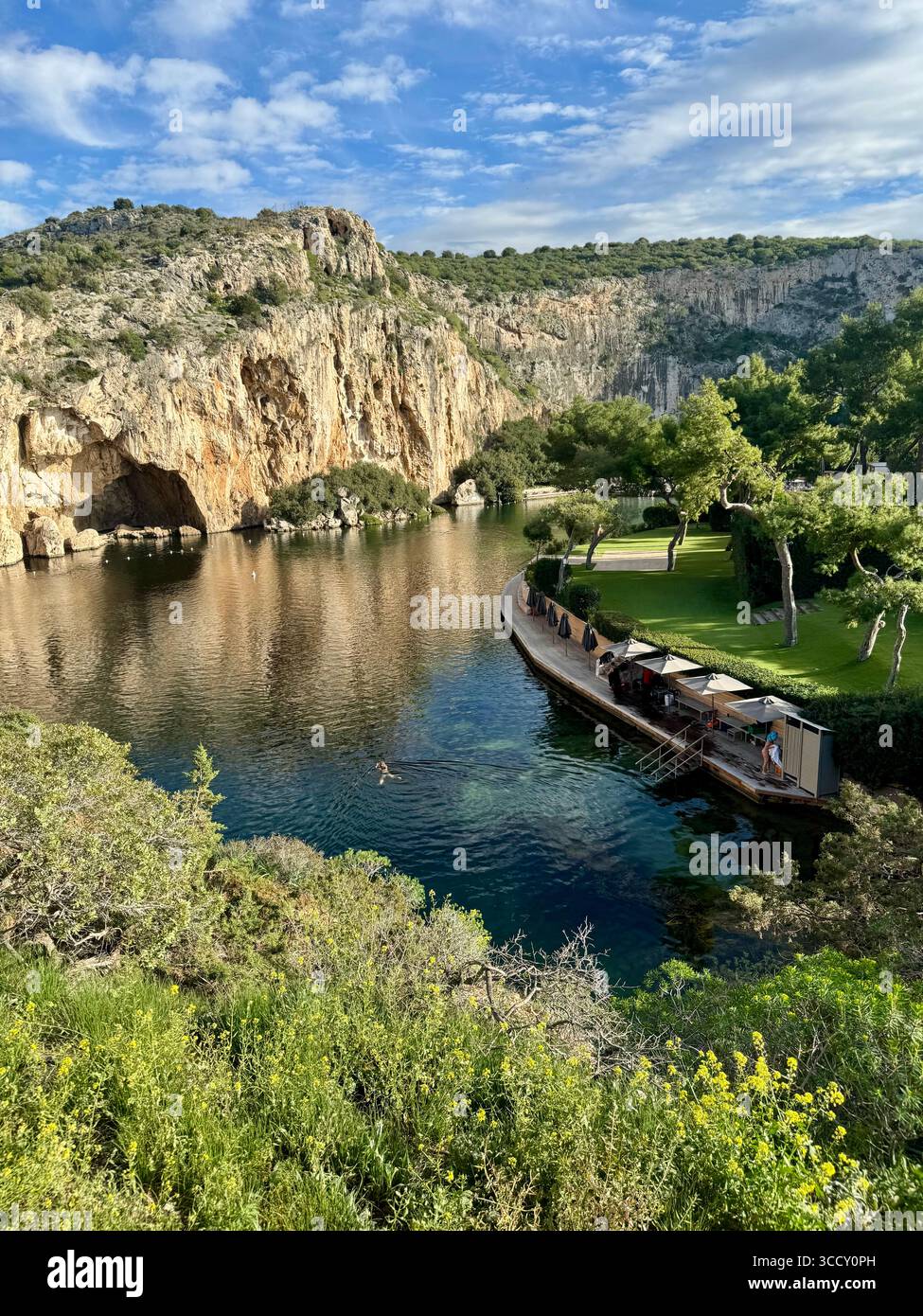 Thermal Spa Lake Vouliagmeni, a natural geothermal lake surrounded by cliffs and lush greenery in Greece. - Smartphone Captured Stock Image