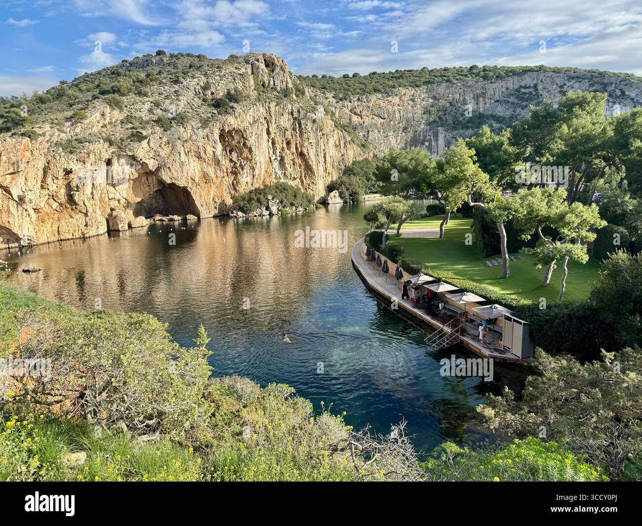 Thermal Spa Lake Vouliagmeni, a natural geothermal lake surrounded by cliffs and lush greenery in Greece. - Smartphone Captured Stock Image