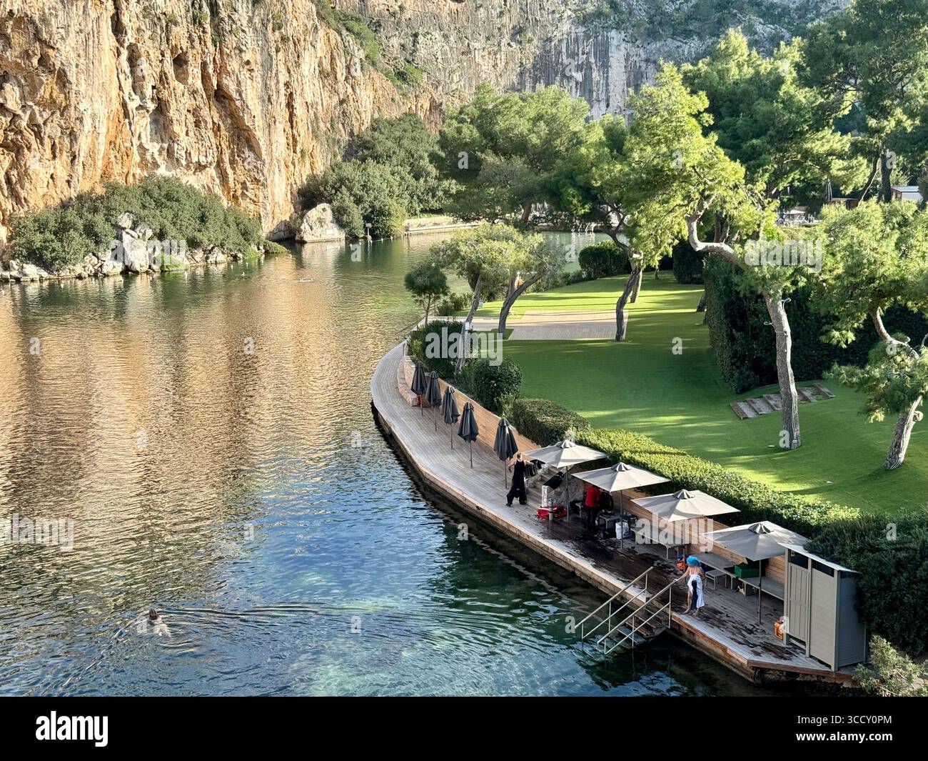 Thermal Spa Lake Vouliagmeni, a natural geothermal lake surrounded by cliffs and lush greenery in Greece. - Smartphone Captured Stock Image