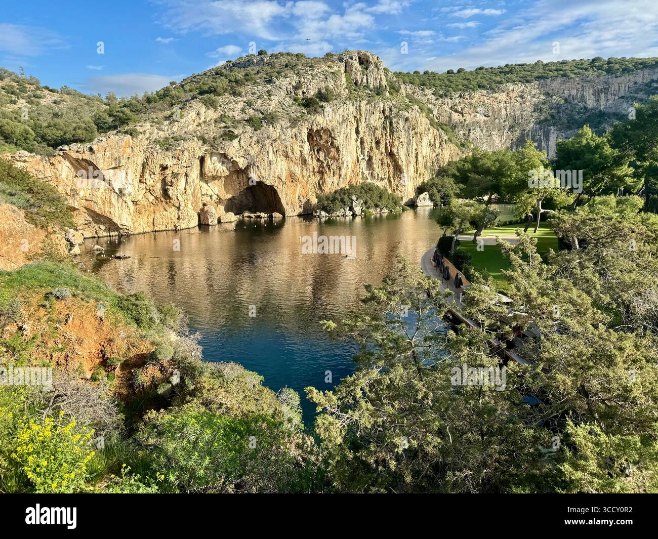 Thermal Spa Lake Vouliagmeni, a natural geothermal lake surrounded by cliffs and lush greenery in Greece. - Smartphone Captured Stock Image