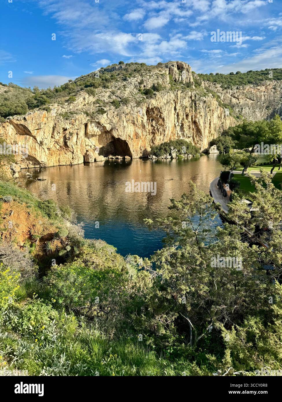Thermal Spa Lake Vouliagmeni, a natural geothermal lake surrounded by cliffs and lush greenery in Greece. - Smartphone Captured Stock Image