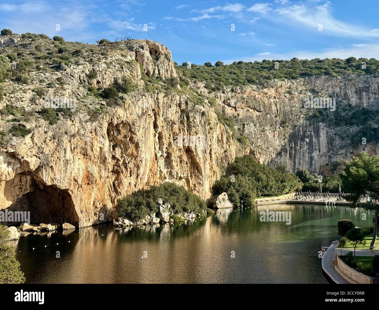 Thermal Spa Lake Vouliagmeni, a natural geothermal lake surrounded by cliffs and lush greenery in Greece. - Smartphone Captured Stock Image