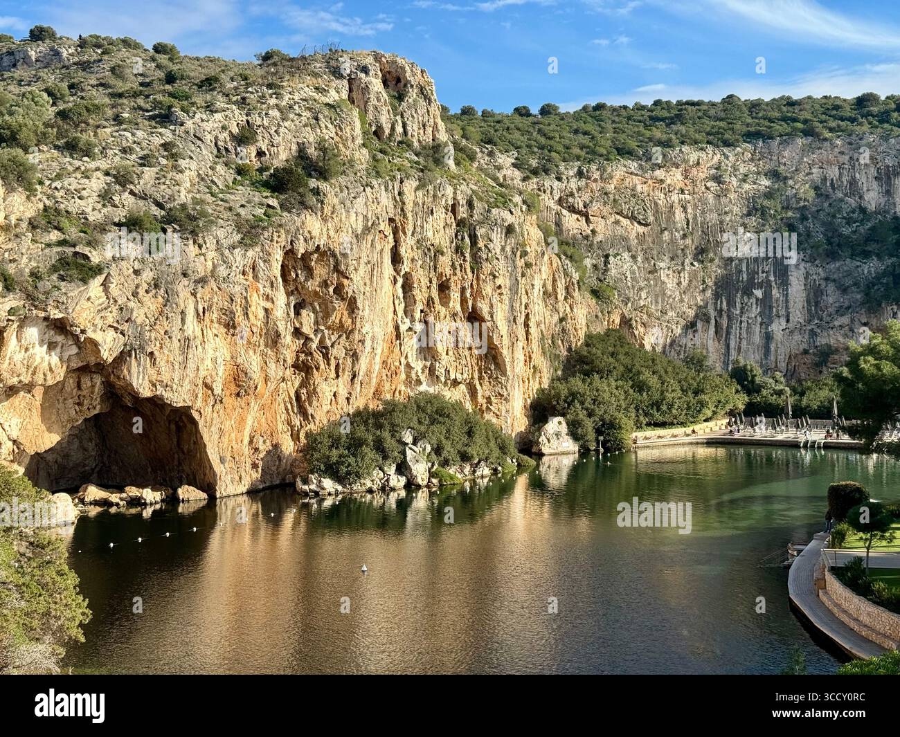 Thermal Spa Lake Vouliagmeni, a natural geothermal lake surrounded by cliffs and lush greenery in Greece. - Smartphone Captured Stock Image