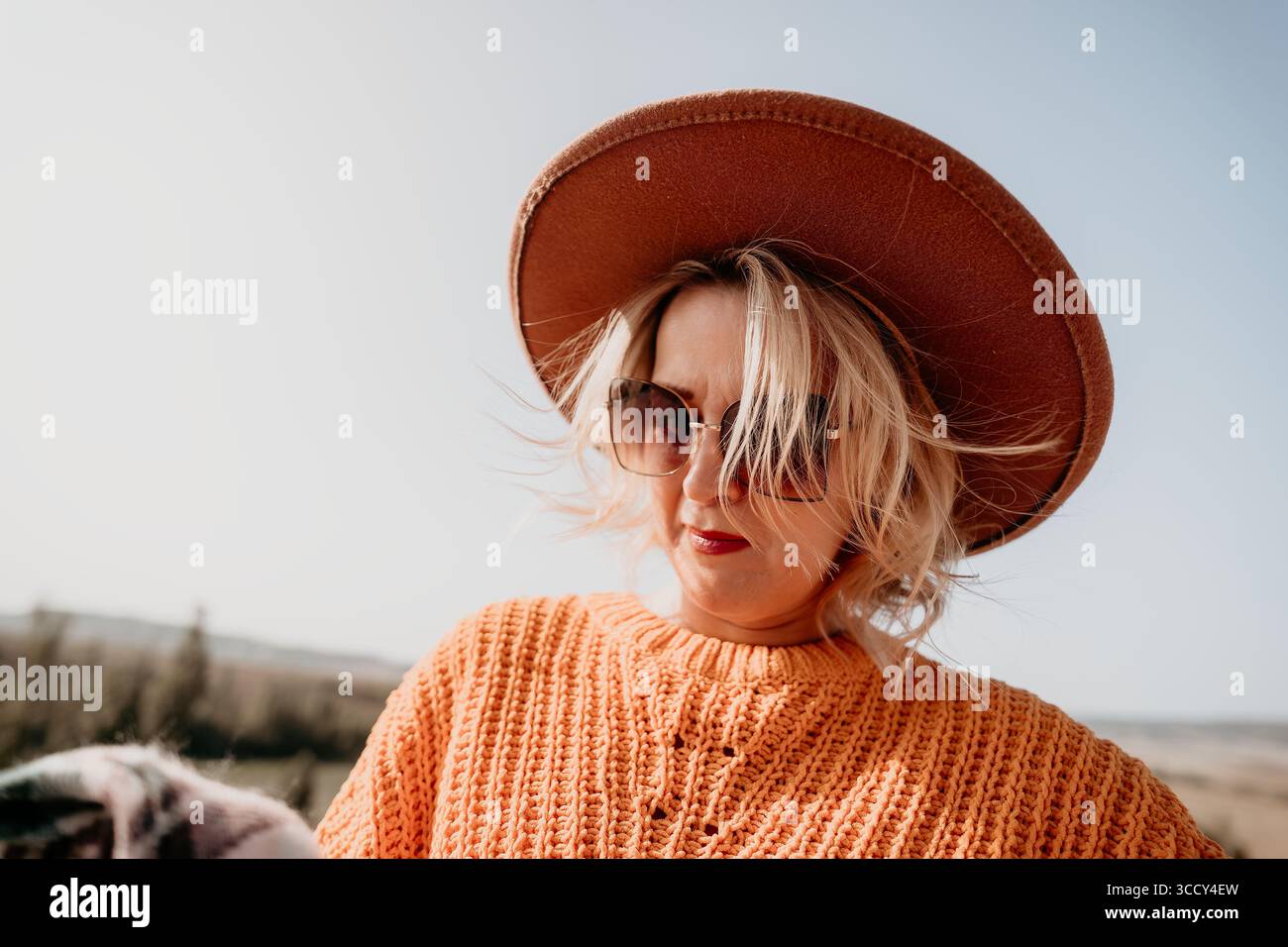 Woman in a Hat and Sunglasses Looking Down Stock Photo