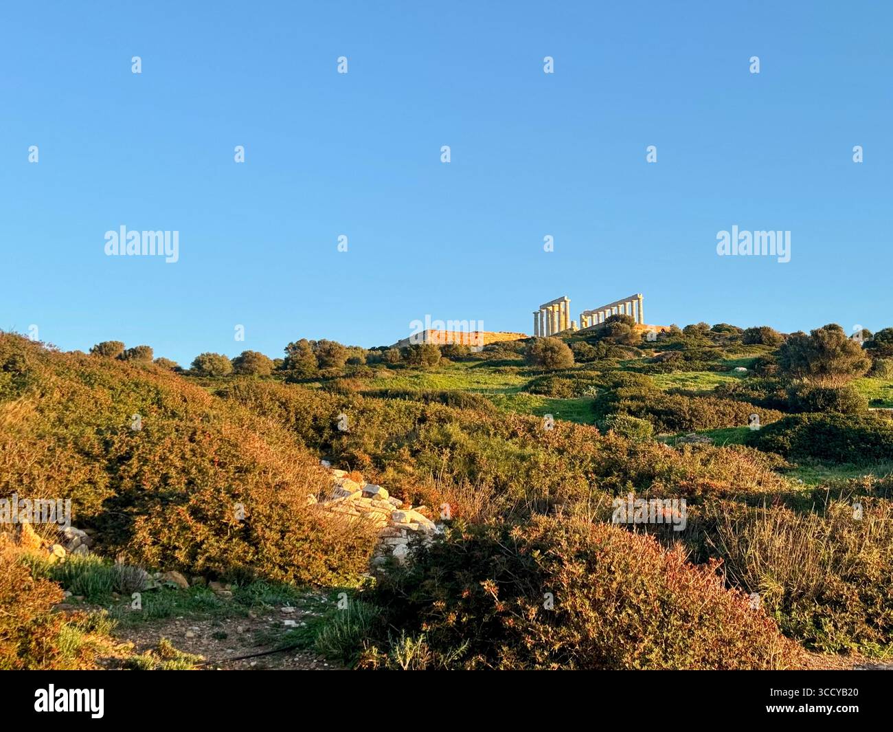 Golden hour light bathes the archaeological site of Sounion, Greece, including pathways and ruins near the Temple of Poseidon. - Smartphone Captured Stock Image