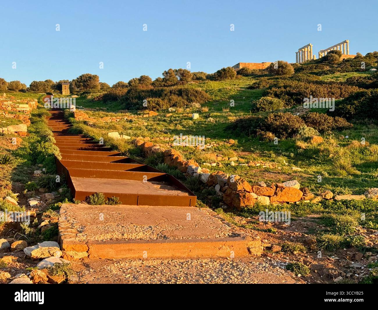 Golden hour light bathes the archaeological site of Sounion, Greece, including pathways and ruins near the Temple of Poseidon. - Smartphone Captured Stock Image