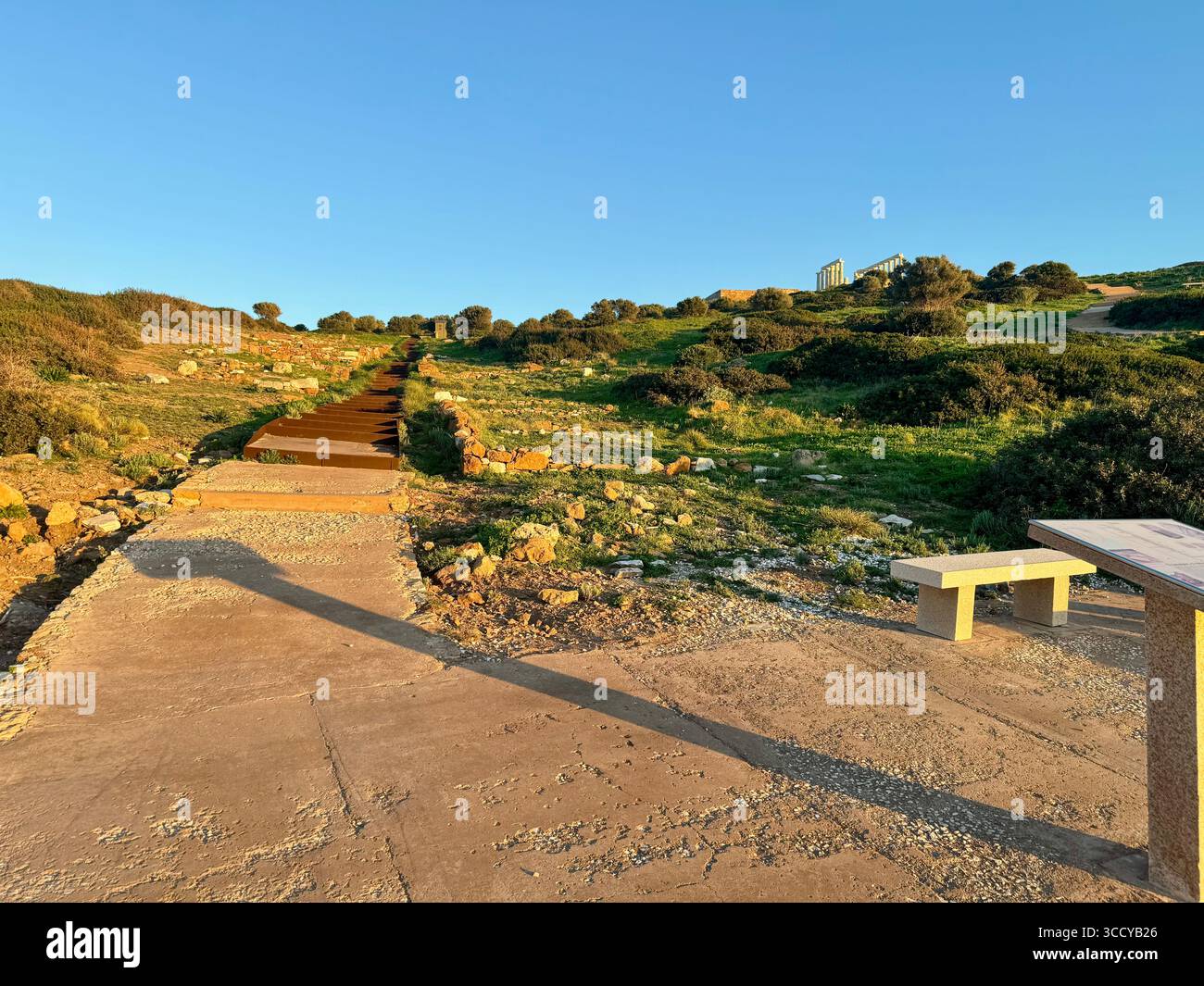Golden hour light bathes the archaeological site of Sounion, Greece, including pathways and ruins near the Temple of Poseidon. - Smartphone Captured Stock Image