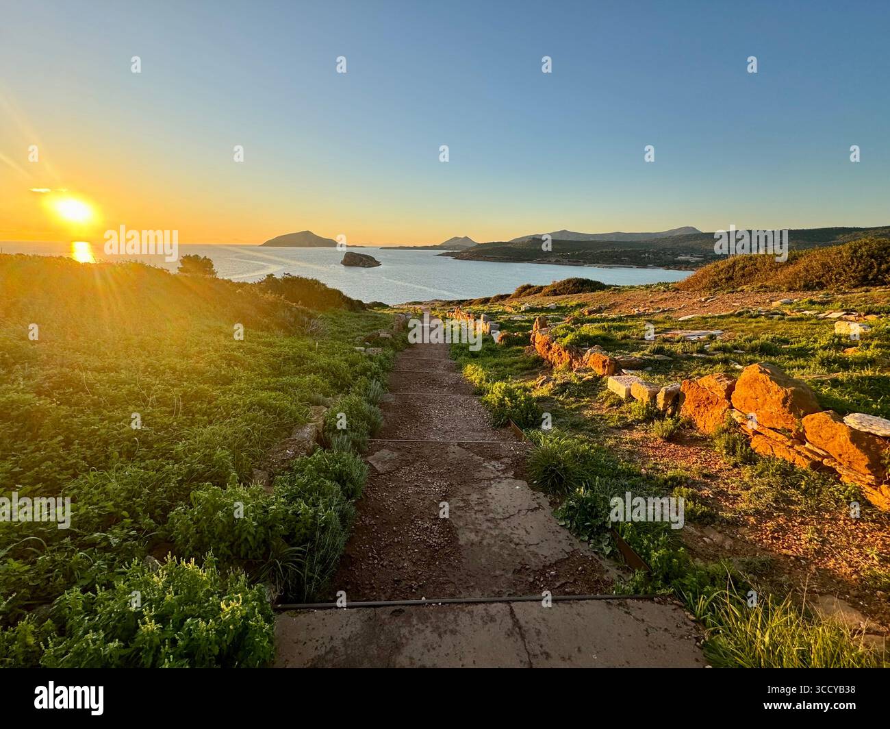 Golden hour light bathes the archaeological site of Sounion, Greece, including pathways and ruins near the Temple of Poseidon. - Smartphone Captured Stock Image