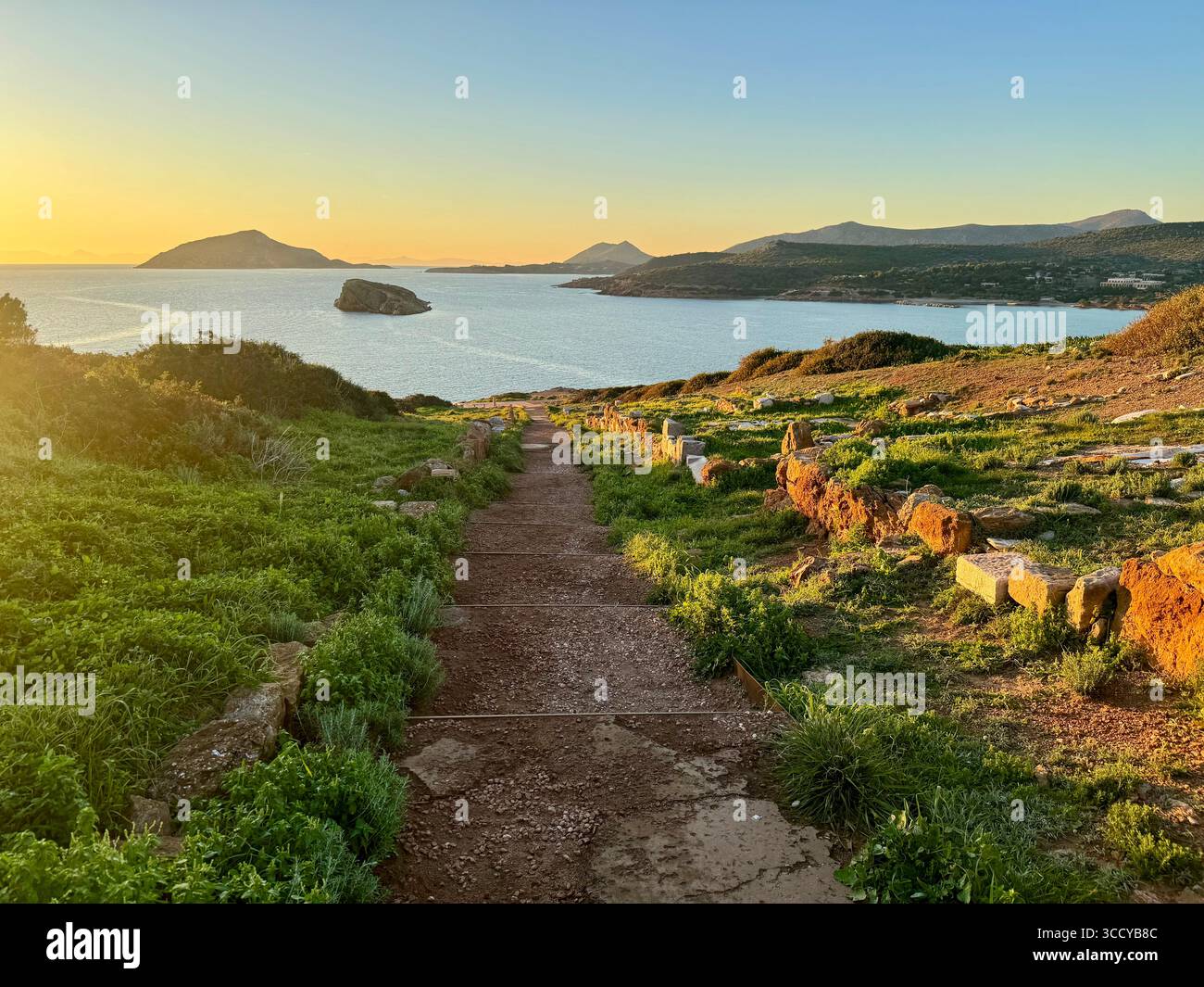 Golden hour light bathes the archaeological site of Sounion, Greece, including pathways and ruins near the Temple of Poseidon. - Smartphone Captured Stock Image