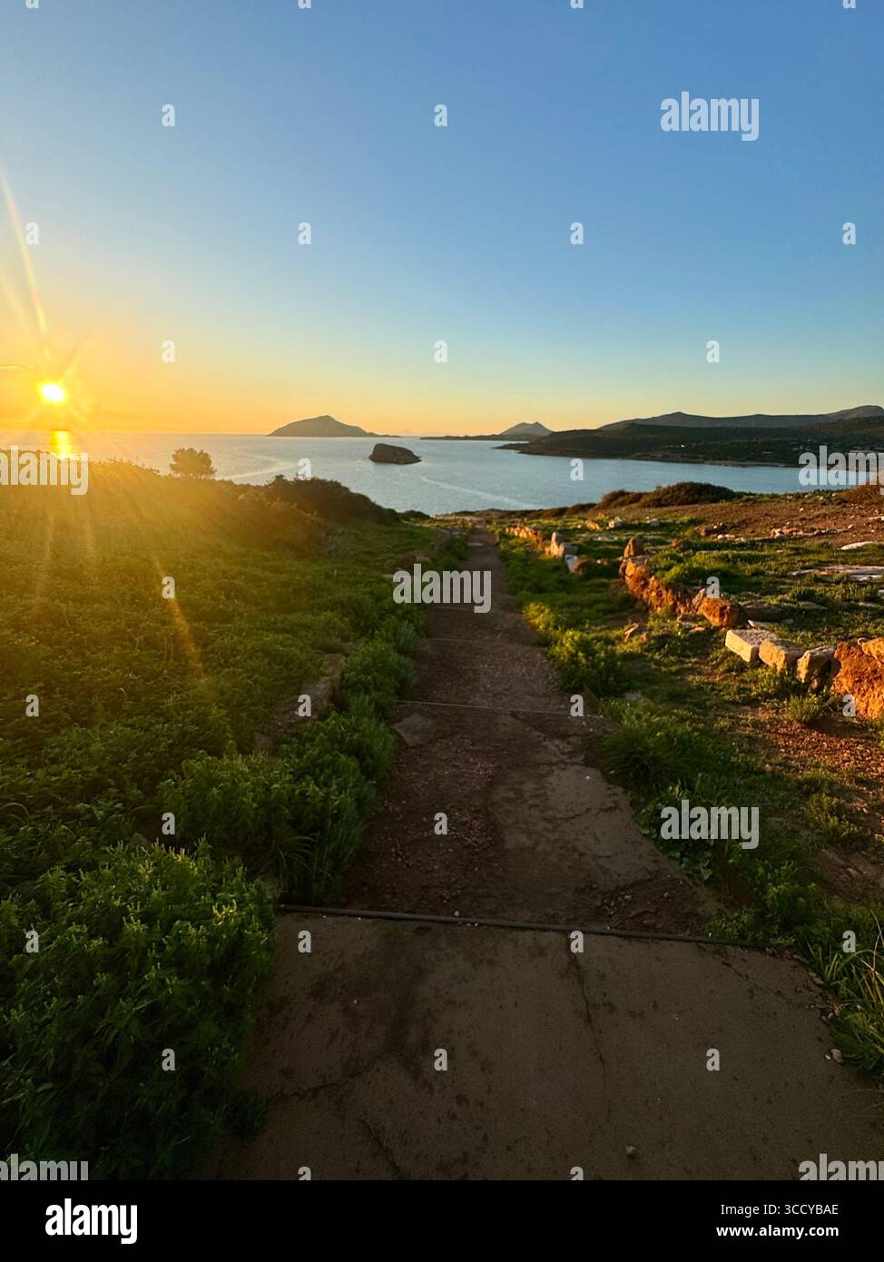Golden hour light bathes the archaeological site of Sounion, Greece, including pathways and ruins near the Temple of Poseidon. - Smartphone Captured Stock Image