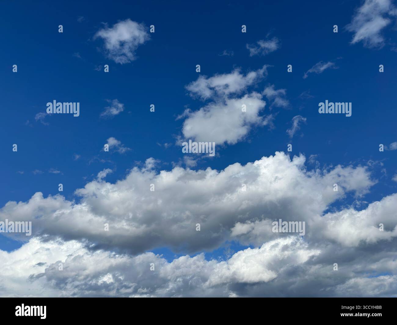 Bright blue sky filled with fluffy white clouds on a beautiful day. - Smartphone Captured Stock Image