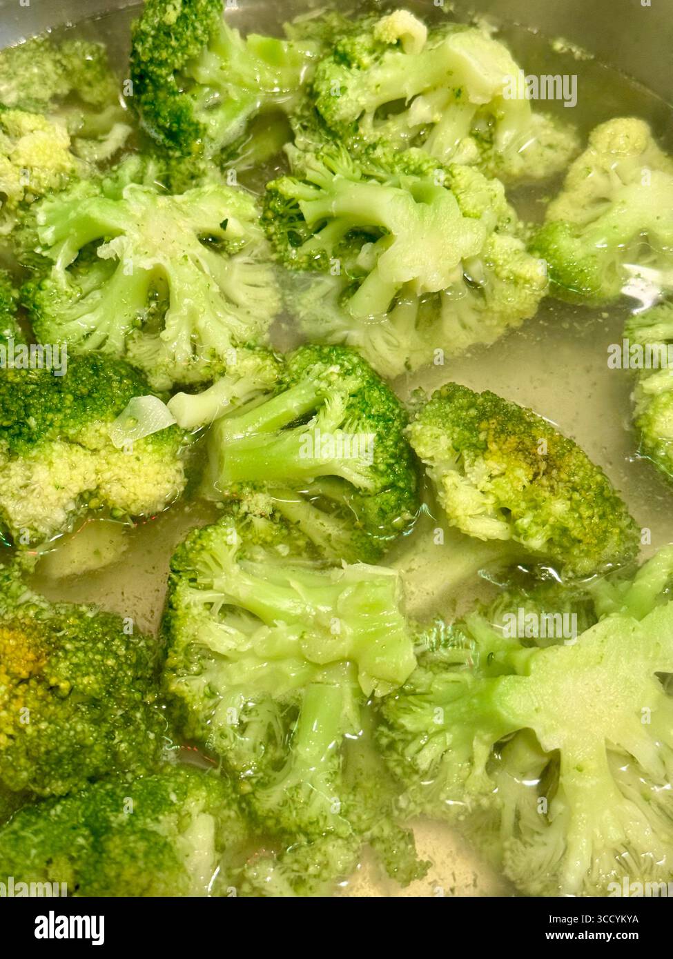 Fresh broccoli florets boiling in water during cooking. - Smartphone Captured Stock Image