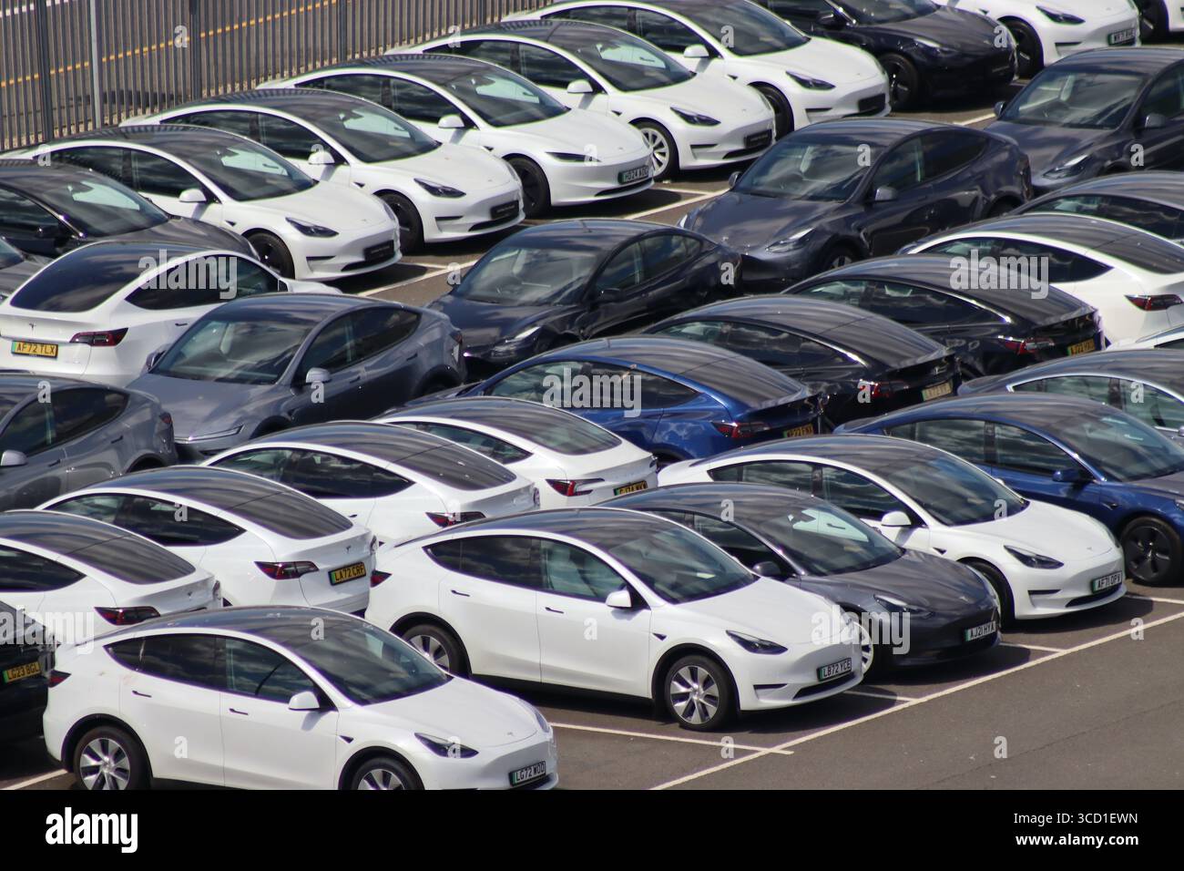 A tranche of Tesla electric vehicles in storage awaiting new owners. While some vehicles appear road registered, only a few can be driven away. Stock Photo