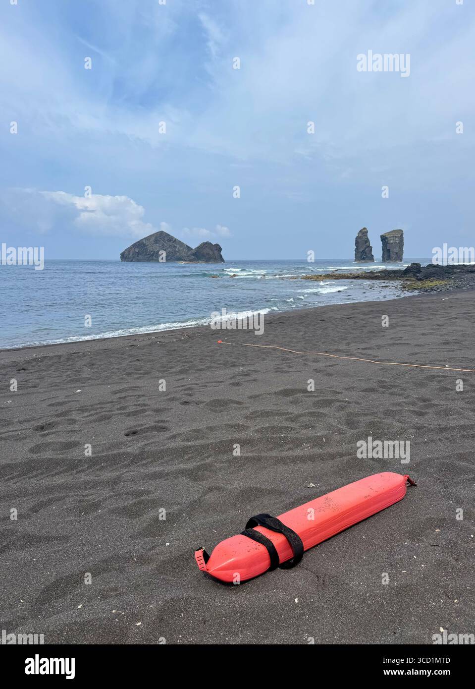 Orange lifeguard rescue belt buoy on the black sand of Mosteiros Beach, Azores. - Smartphone Captured Stock Image