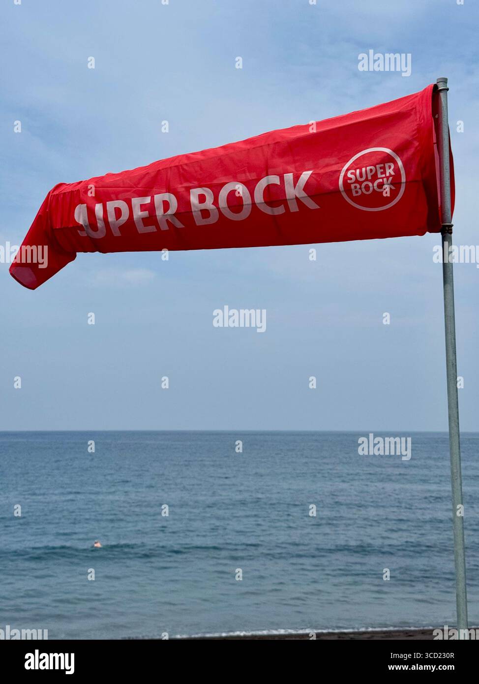 Red Super Bock windsock blowing in the wind on a beach in Portugal. - Smartphone Captured Stock Image