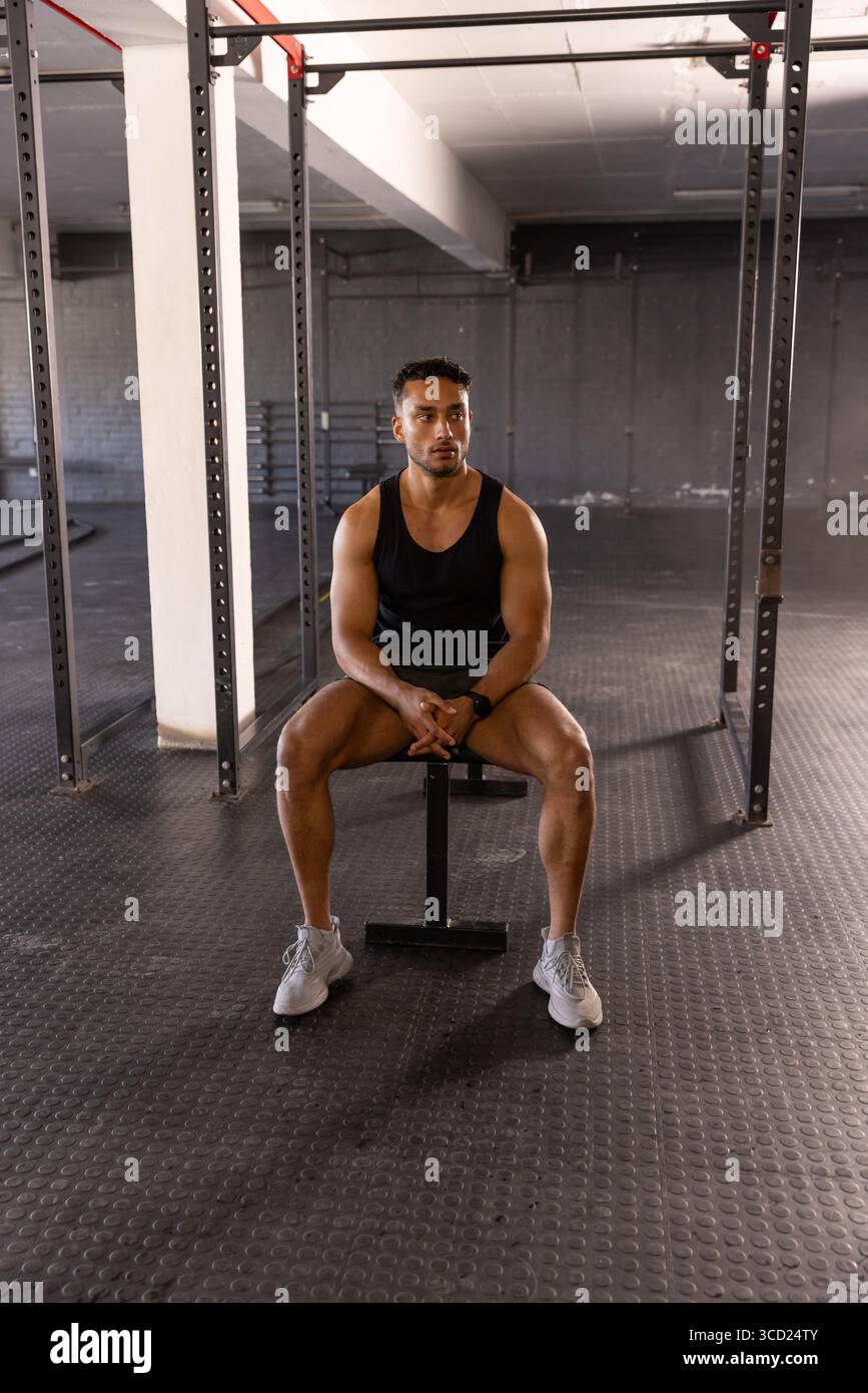 Hispanic Rack Hispanic male athlete sitting on bench beside squat rack with pull-up ...