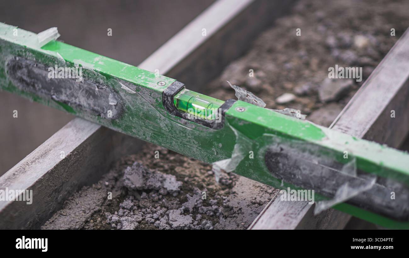 A spirit level rests on concrete to ensure surface evenness, an essential step in maintaining precision and quality in construction work Stock Photo