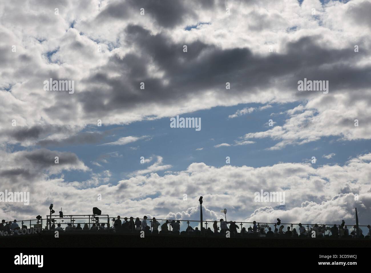 View of fans sitting on upper court level with dark clouds looming above at the 2025 Wimbledon Championships, London, England, United Kingdom Stock Photo