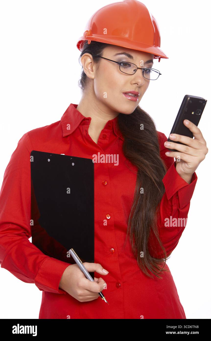 Female architect holding clipboard, using cell phone Stock Photo